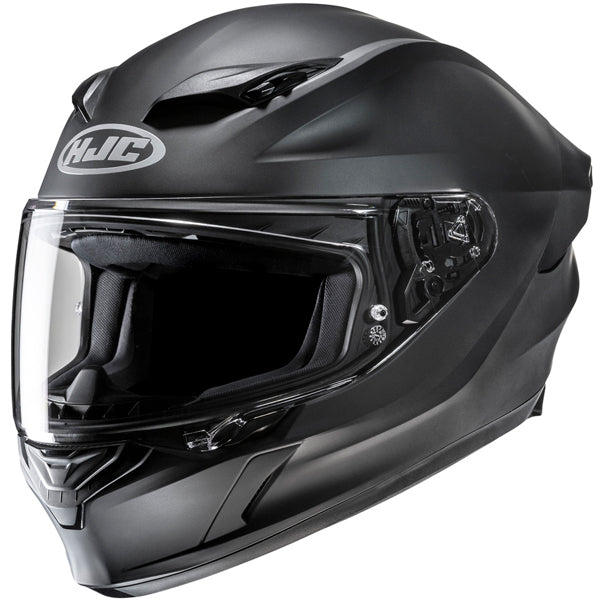 810017703 | A sleek, matte black full-face motorcycle helmet with a clear visor, featuring the HJC logo on the front, aerodynamic design with vents on top, and detailed internal padding visible through the open visor, set against a plain white background with soft lighting highlighting its contours. | Available at BTO Sports