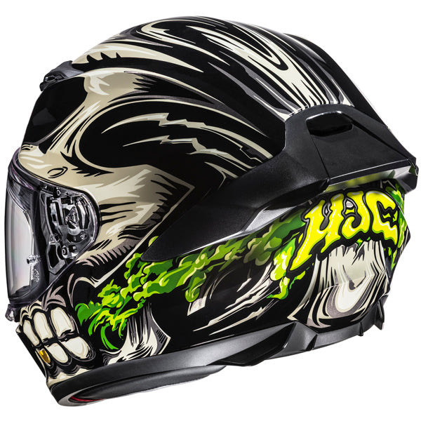 A full-face motorcycle helmet with a black base color featuring a graphic design of a skull with sharp, angular features in beige and black, with green slime-like accents flowing from the skull's mouth. The helmet has a clear visor with visible mechanical components and hinges, and a black aerodynamic vent on top. The background is plain white, emphasizing the helmet's detailed artwork, with bright lighting highlighting the glossy finish and vibrant colors, creating a bold and edgy mood. The style is modern - alternate view
