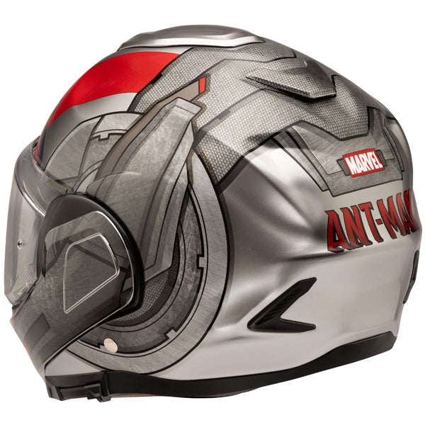 A Marvel Ant-Man themed motorcycle helmet with a sleek, aerodynamic design featuring a silver, black, and red color palette. The helmet displays detailed graphic artwork of Ant-Man's suit, including textured patterns and angular lines, with the Marvel logo and 'ANT-MAN' text prominently on the back. It has a clear visor with a black trim, positioned at a slight angle, and the background is plain white, emphasizing the helmet's futuristic and stylish appearance. The lighting highlights the metallic finish an