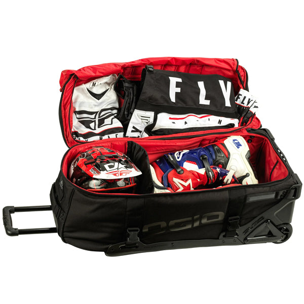 OGIO RIG 9800 DNGR X gear bag lying open with bright red interior, showing divided compartments packed with motocross helmet, boots, and Fly Racing gear, SKU 80100025 | Available at BTO Sports
