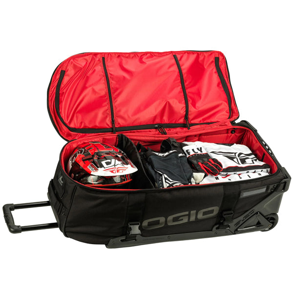 OGIO RIG 9800 DNGR X bag open with lid raised to show red interior and multiple lid pockets, main compartment packed with folded jerseys, pants, and helmet in separate divider, SKU 80100025 | Available at BTO Sports