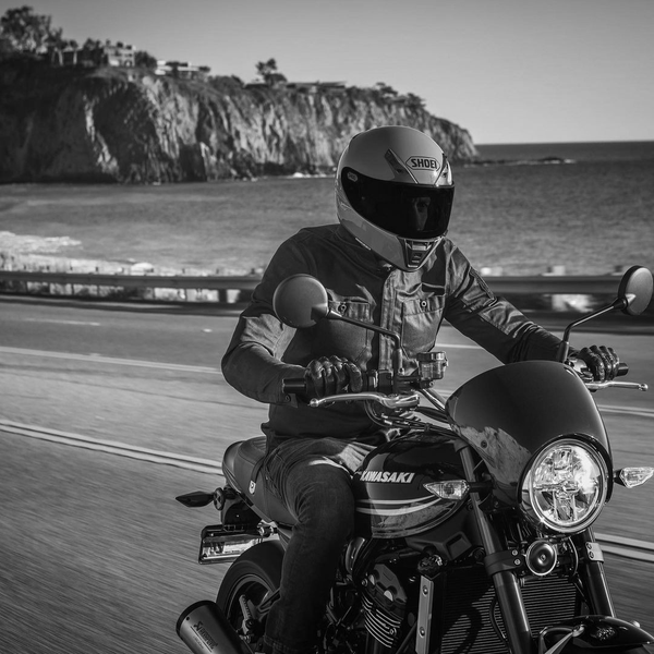 man riding a motorcycle by the ocean in a shoei helmet collection