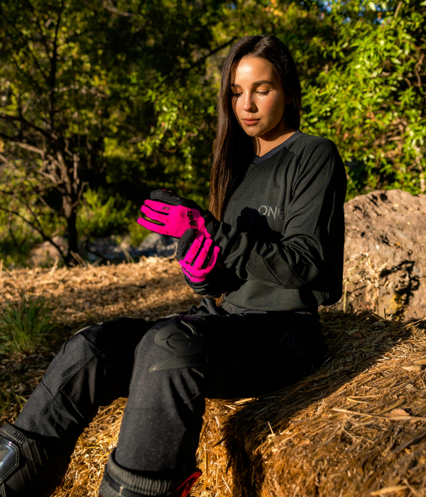 Female rider wearing O'Neal women's motocross apparel and pink riding gloves while preparing for a trail ride outdoors. collection