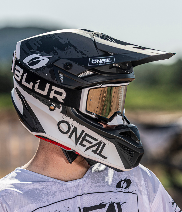 Close-up side profile of an O'Neal Blur motocross helmet with mirrored goggles worn by a rider outdoors. collection