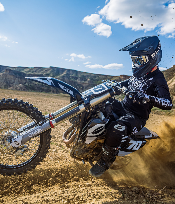 Rider wearing O'Neal black motocross gear carving a dirt bike through a berm on an off-road motocross track. collection
