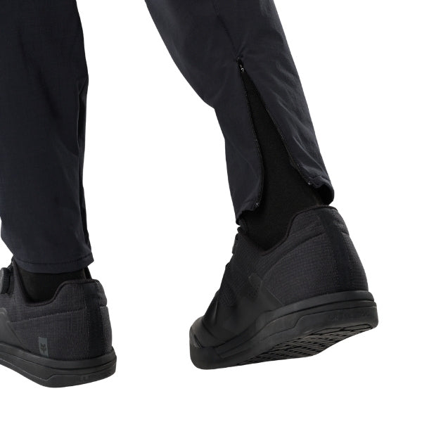 Fox Racing Flexair Fire Pants (MTB) in Black, rear lower-leg and cuff view, with the reinforced seat, rear yoke, articulated knees, tapered legs, and lower-leg graphics. Available options—Color: Black, Nutmeg, Galaxy Blue; Size: 28, 30, 32, 34, 36, 38, 40. SKU 40142-001-38. UPC 198571106464.