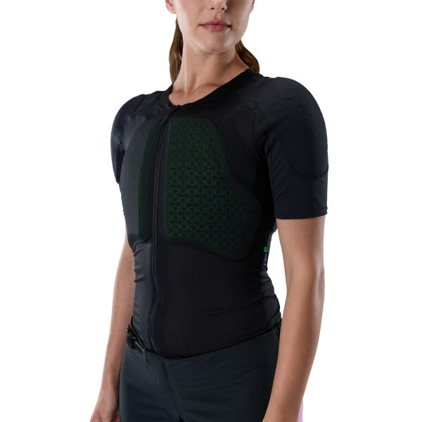 Fox Racing Baseframe Pro Short Sleeve (Womens) in Black, modeled chest and shoulder view, with the green perforated impact panel, black mesh stretch fabric, flat seams, and close-fitting cut on a rider. Available options—Color: Black; Size: SM, MD, LG. SKU 38398-001-L. UPC 198571133422.