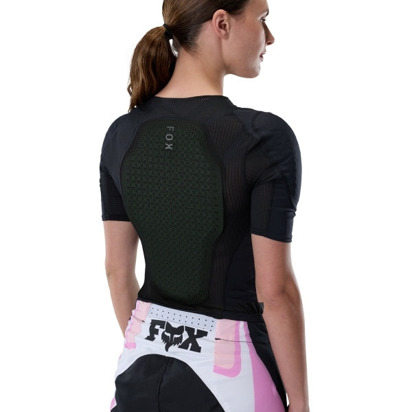 Fox Racing Baseframe Pro Short Sleeve (Womens) in Black, close-up of the side opening or zipper, with the green perforated impact panel, black mesh stretch fabric, flat seams, and close-fitting cut on a rider. Available options—Color: Black; Size: SM, MD, LG.