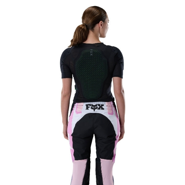 Fox Racing Baseframe Pro Short Sleeve (Womens) in Black, modeled upper-body rear view, with the fitted black mesh body, integrated perforated back-impact panel, shoulder seams, and Fox waist lettering. Available options—Color: Black; Size: SM, MD, LG.