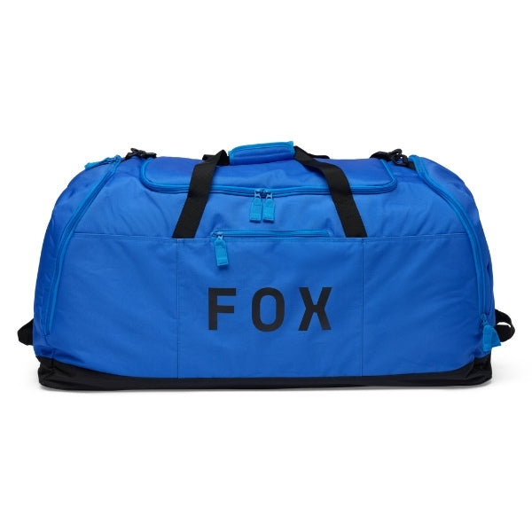 Fox Racing Podium Duffle in Blue Jewel, three-quarter view of the wheeled base and zippered compartments, with the main zippered compartment, reinforced base, carry handles, end pocket, wheels, and large Fox logo. Available options—Color: Black, Red, Blue Jewel.