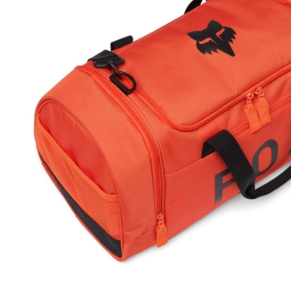 Fox Racing 180 Duffle in Orange, long-side view, with the main zippered compartment, reinforced base, carry handles, end pocket, wheels, and large Fox logo. Available options—Color: Black, Vivid Green, Orange.