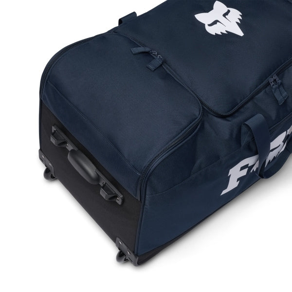 Fox Racing 180 Roller Bag in Midnight, long-side view, with the main zippered compartment, reinforced base, carry handles, end pocket, wheels, and large Fox logo. Available options—Color: Black, Pewter, Midnight.