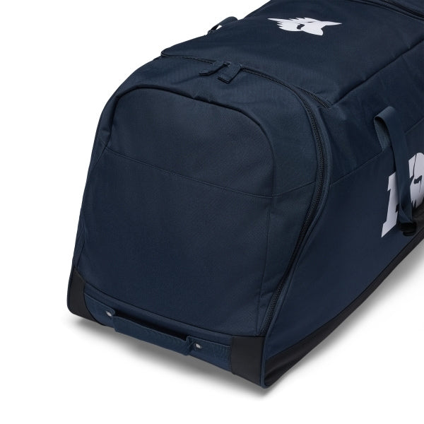 Fox Racing 180 Roller Bag in Midnight, opposite long-side view, with the main zippered compartment, reinforced base, carry handles, end pocket, wheels, and large Fox logo. Available options—Color: Black, Pewter, Midnight.