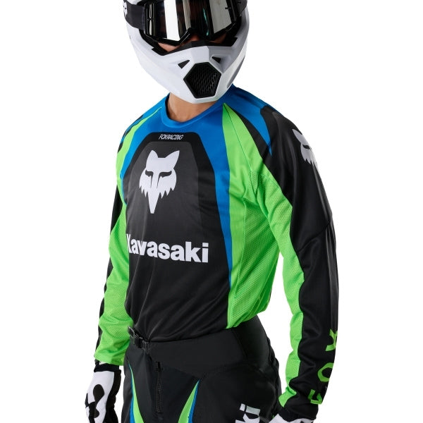 Fox Racing 180 Kawasaki Jersey in Black, modeled front three-quarter view, with the crew neck, long sleeves, contrasting shoulder and arm graphics, and extended rear hem on a rider. Available options—Color: Black; Size: XS, SM, MD, LG, XL, 2X. SKU 40667-001-M. UPC 198571121825.