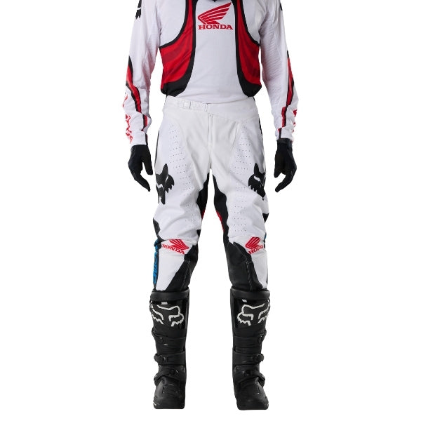 Fox Racing 180 Honda Pants in White/Red, close-up of the side thigh and knee panels, with the ratcheting waist adjuster, stretch yoke, shaped hip panel, and reinforced knee or thigh material. Available options—Color: White/Red; Size: 26, 28, 30, 32, 34, 36, 38. SKU 40708-077-34. UPC 198571132814.