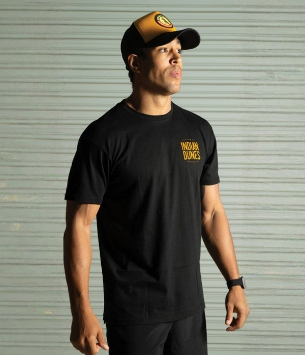 Person wearing a black t-shirt with 'Indian Dunes' logo and a cap, standing against a metallic shutter background. Oneal T-Shirt collection
