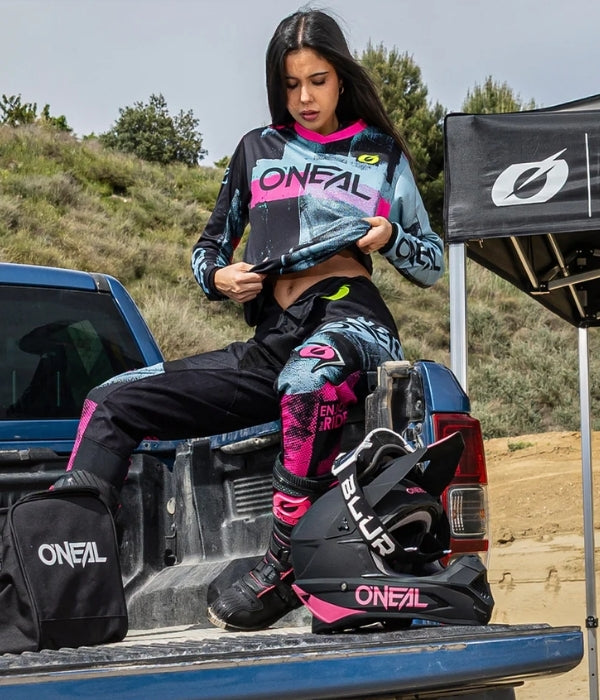 Person wearing O'Neal motocross gear sitting on a truck bed with equipment. Womens O'Neal collection