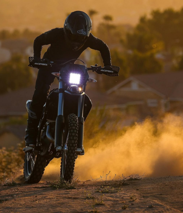 Motocross rider kicking up dust while riding at sunset with warm golden lighting collection