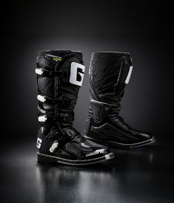 All-black Gaerne Fastback Boots motocross boots in a moody studio setting with reflective floor collection