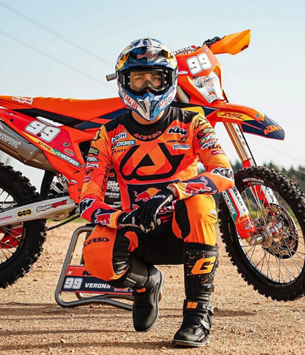 Motocross rider in orange Red Bull KTM gear kneeling beside a dirt bike on a track collection