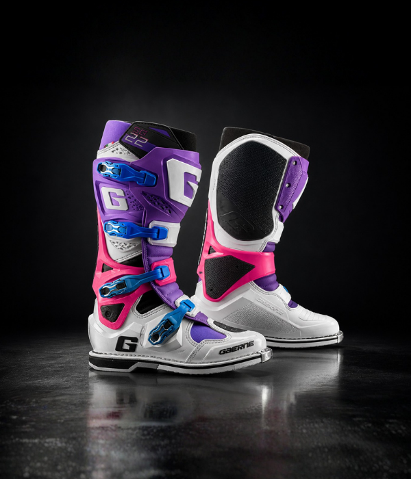 Gaerne SG22 LE motocross boots in white, purple, pink, and blue shown in a dark studio with dramatic lighting collection