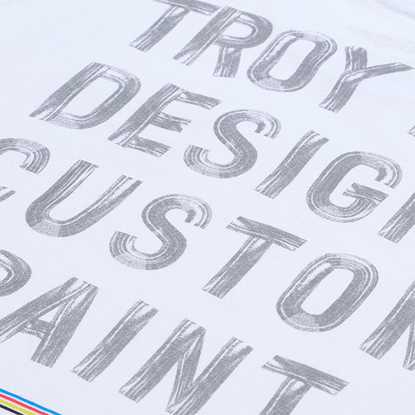 Professional studio photo of Troy Lee Designs Paint Shop Tee; showing tee fit, printed graphics, and crew neckline; SKU 7017290; Colors: Carbon, White