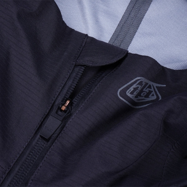 Troy Lee Designs Resist Pro Mono mountain bike jacket in Carbon, close-up highlighting the chest area, visible zipper, branding, and fabric construction