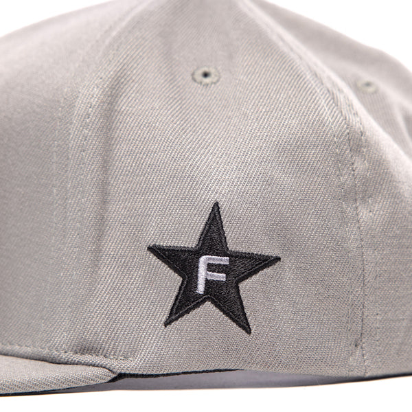 Close-up of the embroidered logo on the right side of the Fasthouse Crown hat, SKU 3210150. A black five-point star with a white