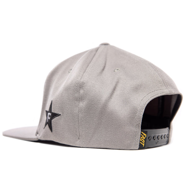 Side-back view of the Fasthouse Crown hat, SKU 3210150. The grey hat features a black star logo with a white