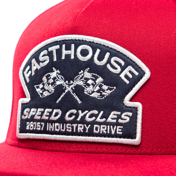 This close-up view of the Fasthouse Crown Hat (SKU 3210150) highlights the embroidered patch on the front crown. The patch is navy blue with white lettering and stitching.