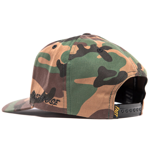 Rear angle of Fasthouse Wired Hat SKU 3321098, camouflage snapback with adjustable closure, yellow woven “Fast” tag detail, and structured motocross-inspired streetwear design.