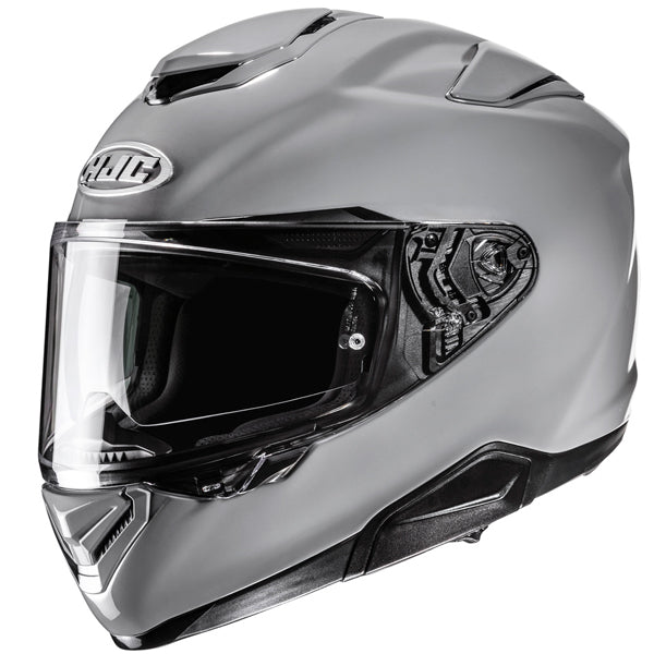 A sleek, modern motorcycle helmet in matte silver with a black tinted visor, featuring aerodynamic contours and subtle black accents on the top and sides, set against a plain white background. The helmet has a prominent logo on the front above the visor, with visible ventilation vents and a clear, reflective visor that is slightly open, revealing the interior padding. The lighting highlights the smooth surface and reflective details, creating a professional, high-tech appearance. - alternate view