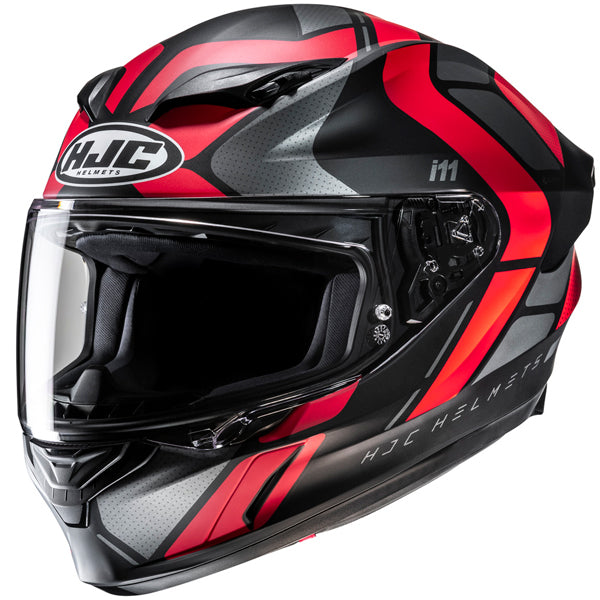 810410103 | A full-face motorcycle helmet with a sleek aerodynamic design, predominantly black with bold red and gray accents, featuring the HJC logo on the front and the model name 'i1' on the side. The helmet has a clear visor, ventilation vents on the top and chin area, and detailed mechanical components on the side for visor adjustment. The background is plain white, emphasizing the helmet's modern, professional style with high-gloss finish and sharp lines. | Available at BTO Sports