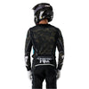 Fox Racing Flexair Apex Jersey in Black, close-up of the lower hem and drop-tail panel, with the printed Fox artwork, mesh-knit texture, reinforced seam lines, and shaped cuff or hem. Available options—Color: Black; Size: SM, MD, LG, XL, 2X.