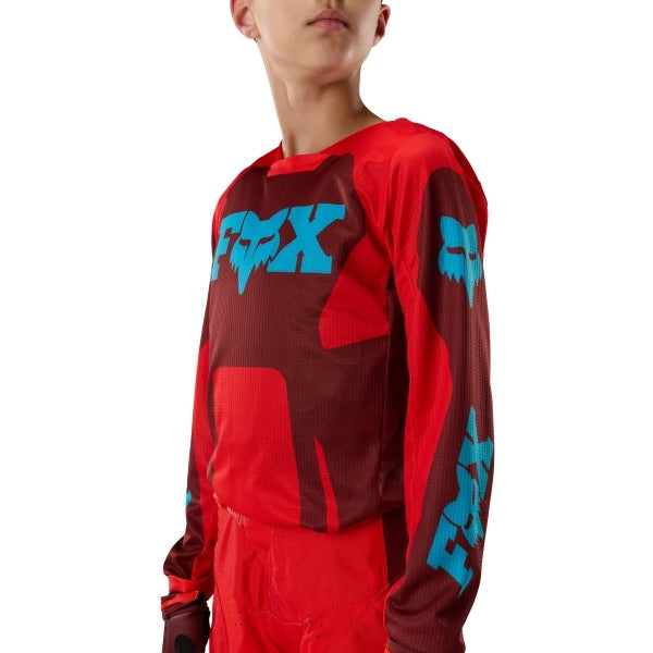 Fox Racing 180 Raid Jersey (Youth) in Rust, modeled front three-quarter view, with the crew neck, long sleeves, contrasting shoulder and arm graphics, and extended rear hem on a rider. Available options—Color: Rust, Purple Lava; Size: Y-SM, Y-MD, Y-LG, Y-XL. SKU 40673-180-YL. UPC 198571130971.