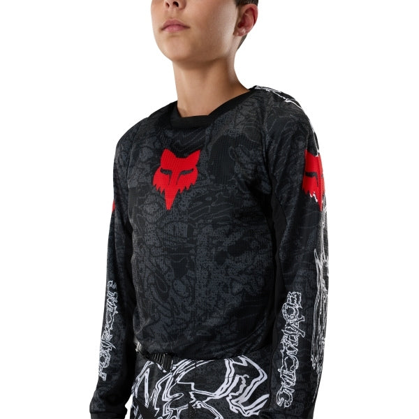 Fox Racing 180 Abyss Jersey (Youth) in Black, modeled front three-quarter view, with the crew neck, long sleeves, contrasting shoulder and arm graphics, and extended rear hem on a rider. Available options—Color: Black; Size: Y-SM, Y-MD, Y-LG, Y-XL. SKU 40680-001-YL. UPC 198571122556.