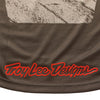 Close-up of the bottom hem of the brown Troy Lee Designs Scout GP Pro jersey, featuring a large, red 